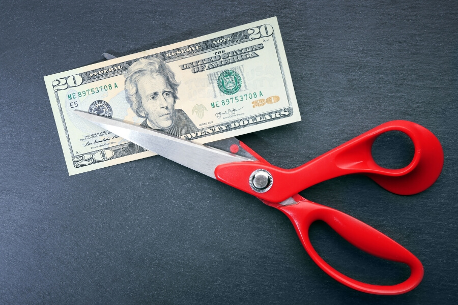 scissor cutting a twenty dollar bill