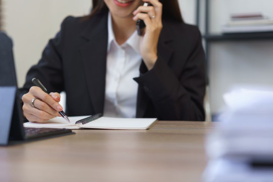 woman talking to phone while writing notes